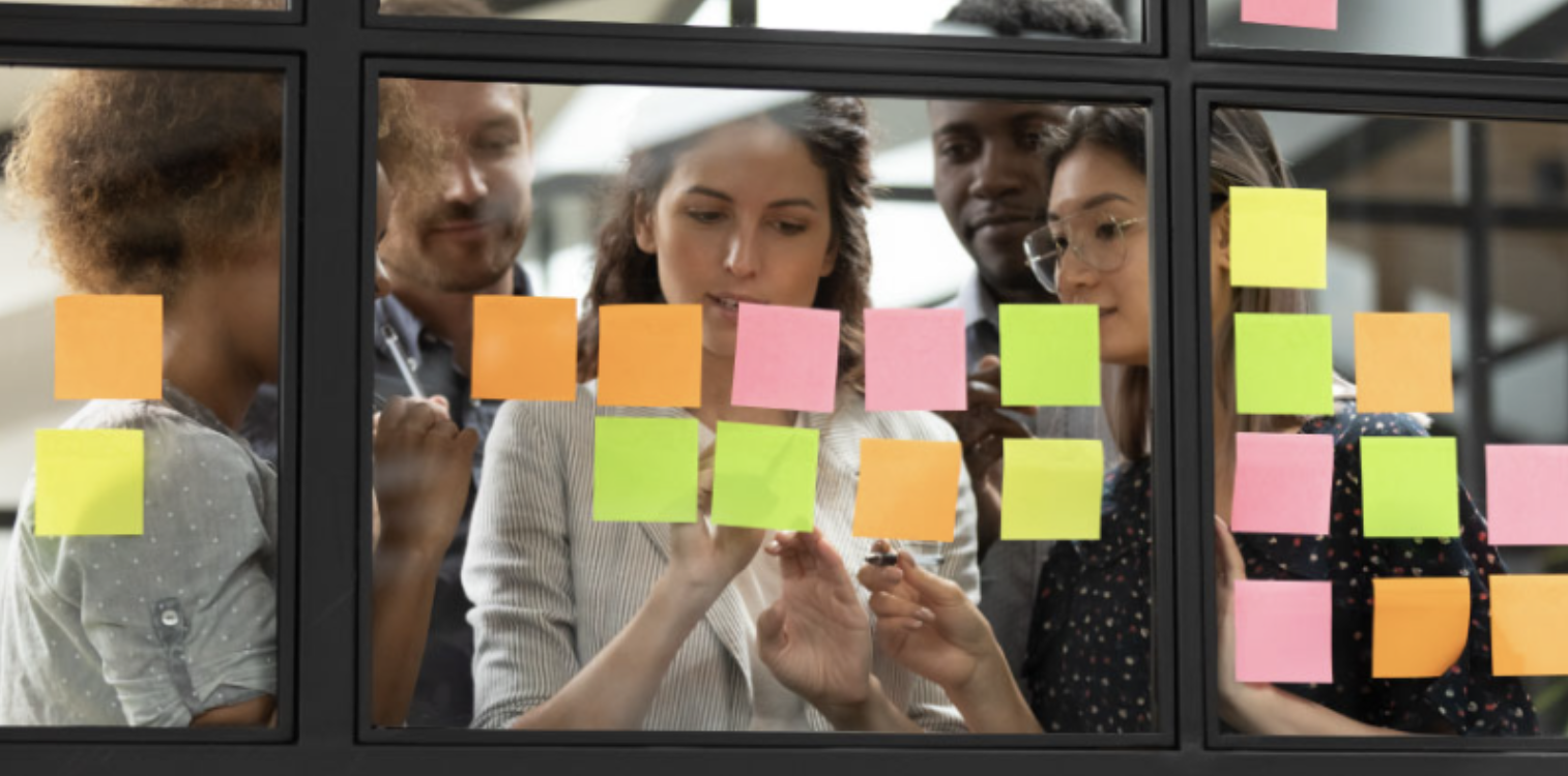 Banner Team of professionals seen through glass wall covered in colorful sticky notes during a collaborative planning session.